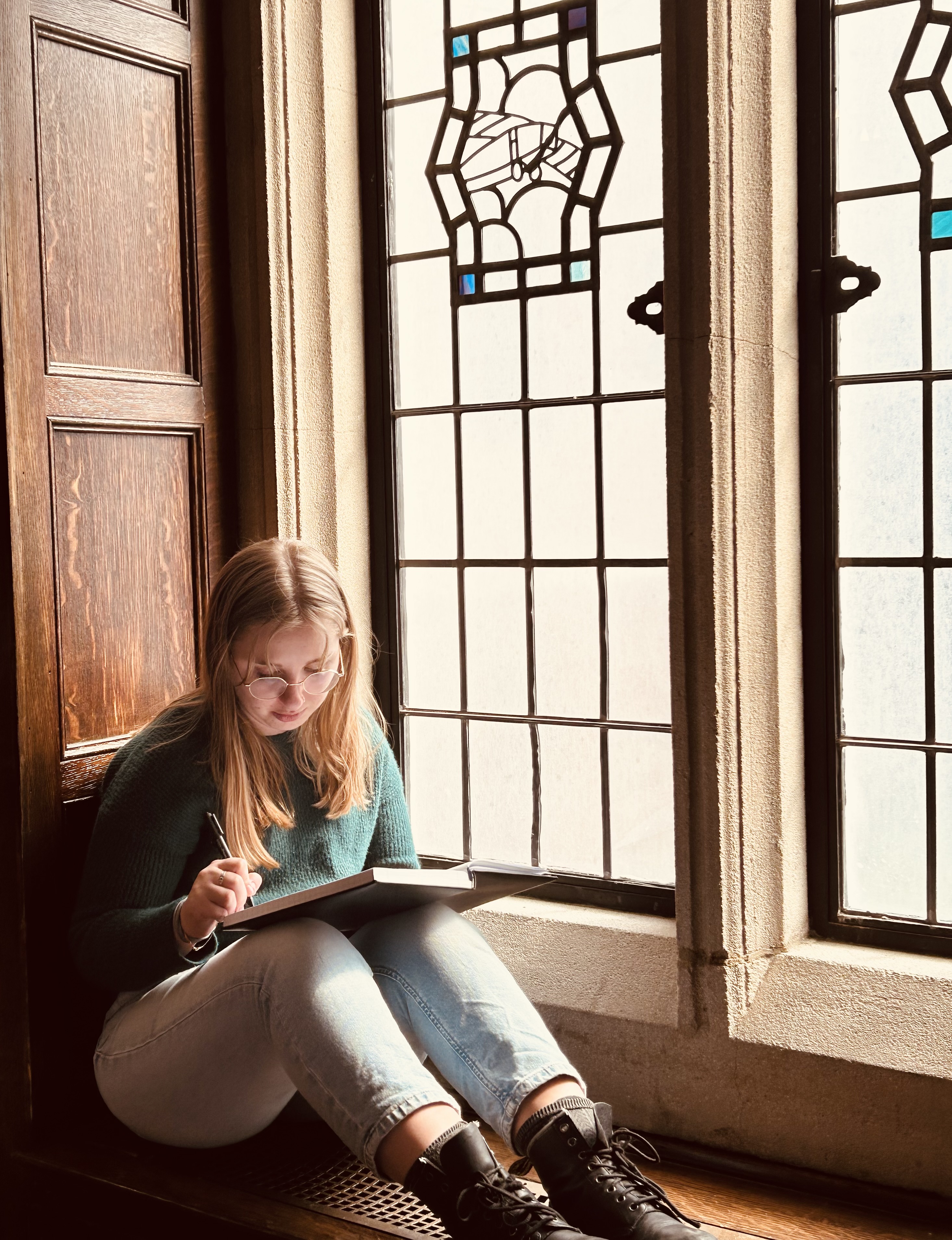Kate Barranco writing in a stained-glass window alcove